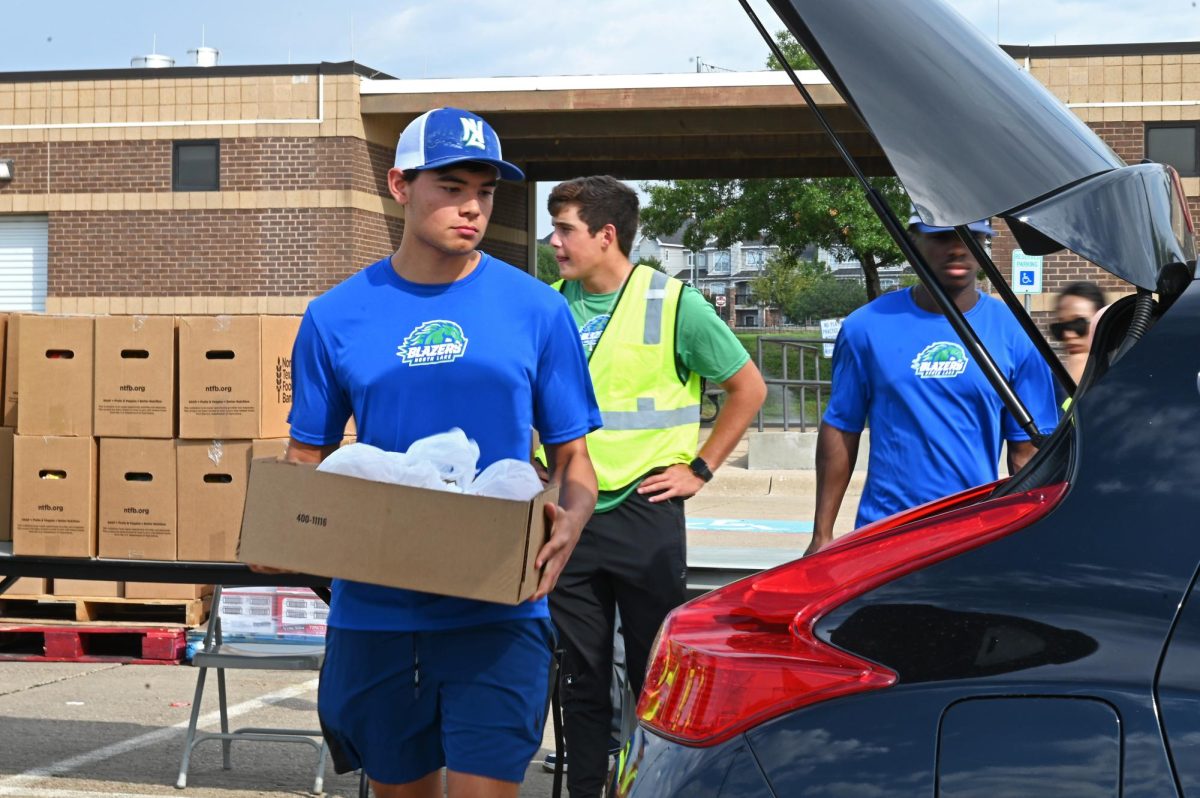 Student athlete Ethan Fancher loads groceries into community members cars during
food pantry drive.