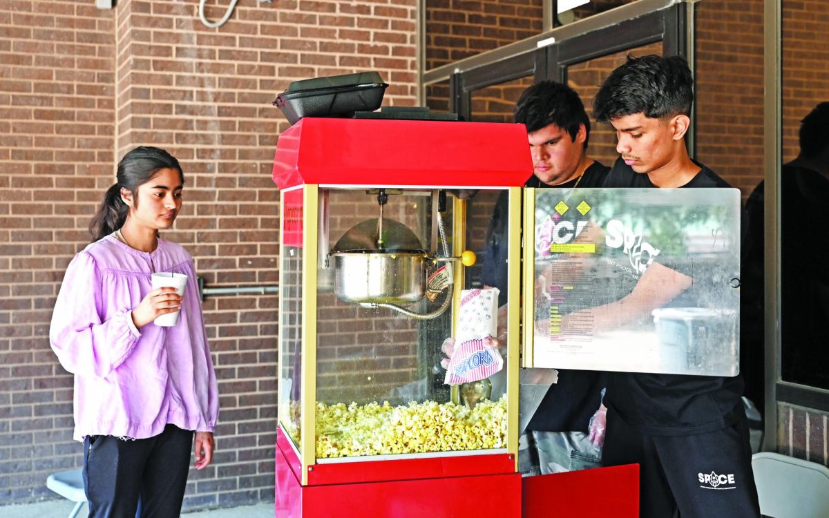 SPACE member Sameen Ahmed (r) serves popcorn to the students at the Fall Fest.