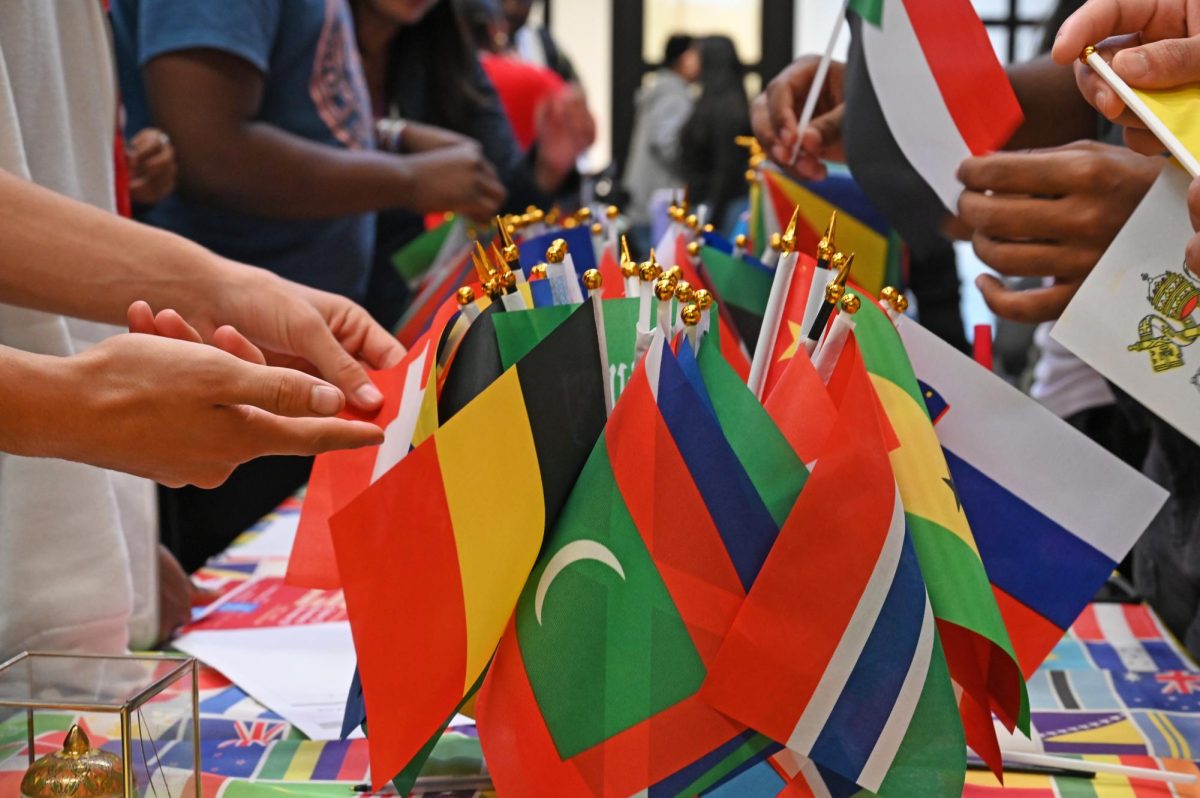 A collection of colorful flags from around the world displayed on a table at the International celebration and given away to students from their respective countries.