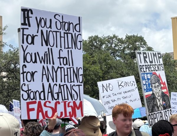 People hold signs at "No Kings" rally in Dallas on June 14.