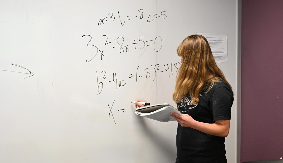 A student works out equation at study room of the Learning Commons in the library.