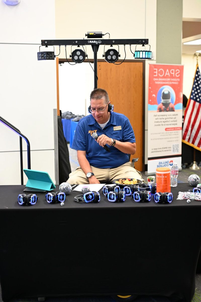 Gus Garza, Jr. provides headphones to students at the Silent Disco event on Sept. 30.