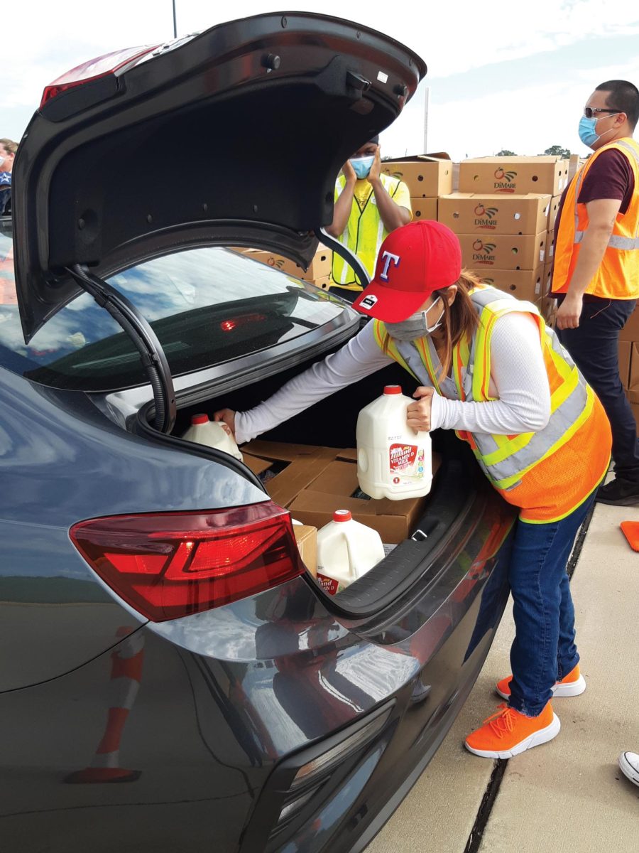 A volunteer distributes food at a drive-through pantry.