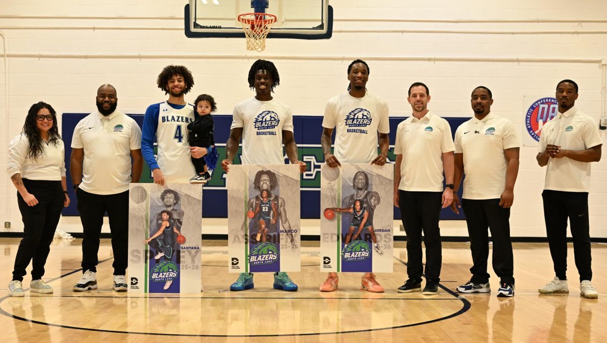 From left, Assistant Coach, Iesha Jackson, Assistant Coach, De'Lano Wilson, Santana Spivey, Marco Assirifix, Jordan Edwards, Head Coach, Josh Mills, Assistant Coach Allen Smith and Assistant Coach Ori Limbrick pose with commemorative posters of the student athletes during Sophmore Night on Feb. 18 in the North Lake gymnasium. 